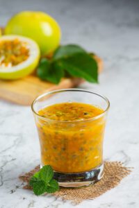 Passion Fruit Juice in a glass with Fruit in the background
